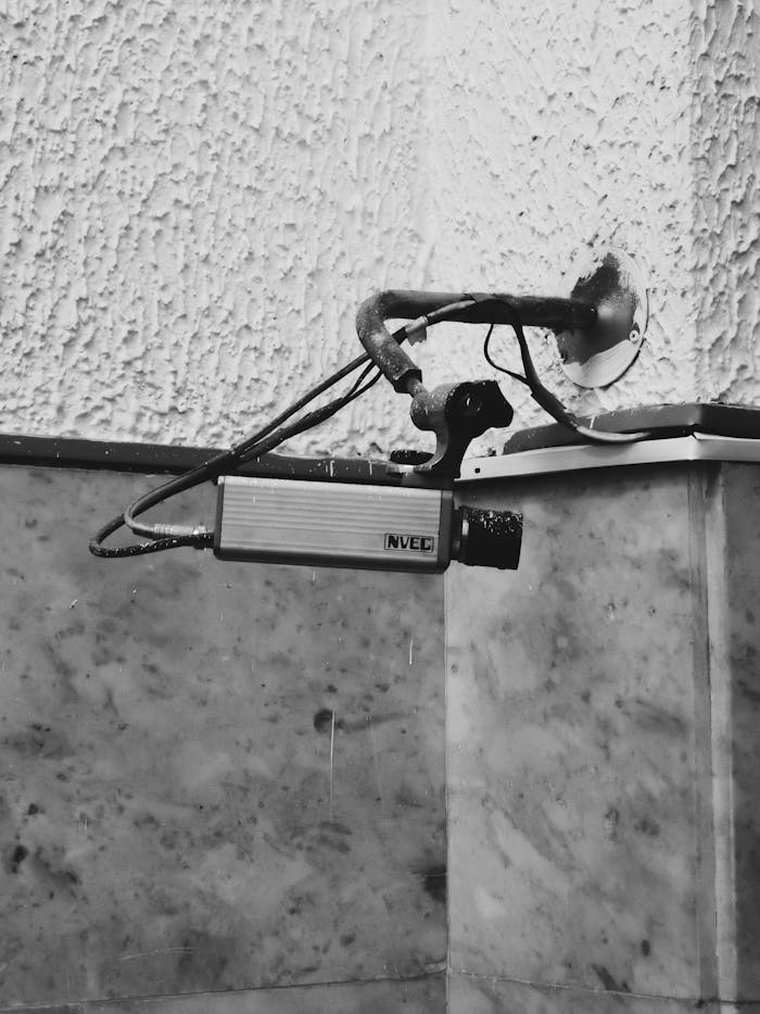 digital Monochrome image of an indoor CCTV camera mounted on a textured wall.