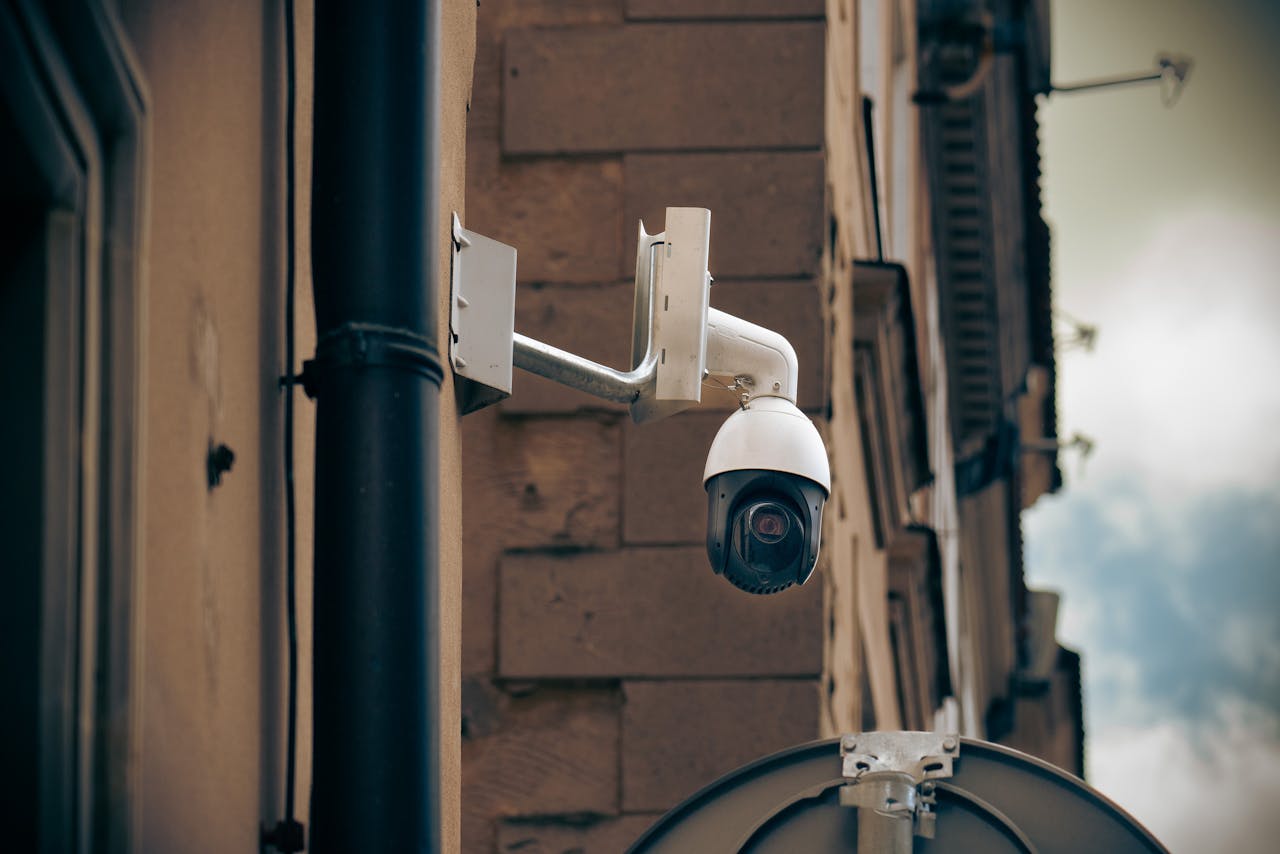 Services-01 CCTV camera mounted on a building wall in an urban street setting, enhancing security.