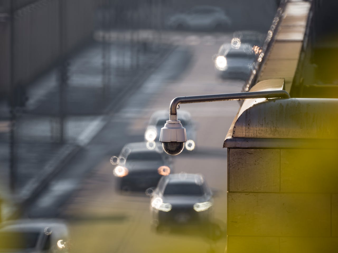 why-choose-us CCTV camera monitoring city traffic on a busy road with blurred vehicles in the background.