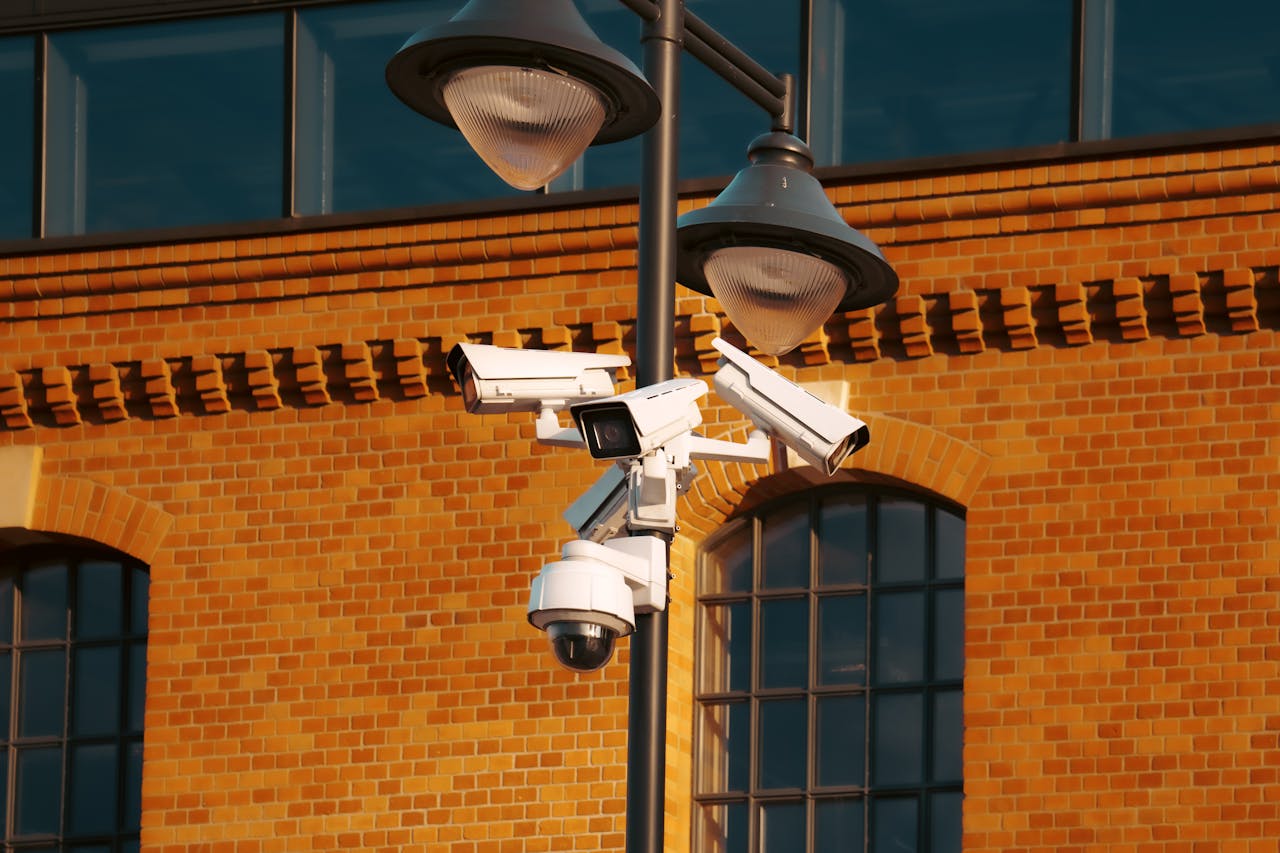 Services-02 Modern security cameras mounted on a pole against a brick building in the city.
