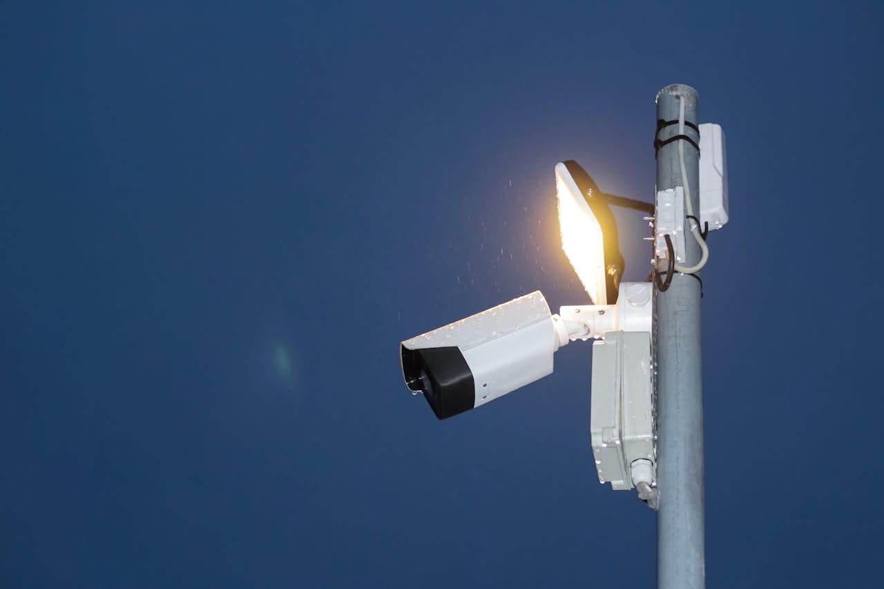 creative-03 Low angle view of a security camera and light against a dark blue night sky.