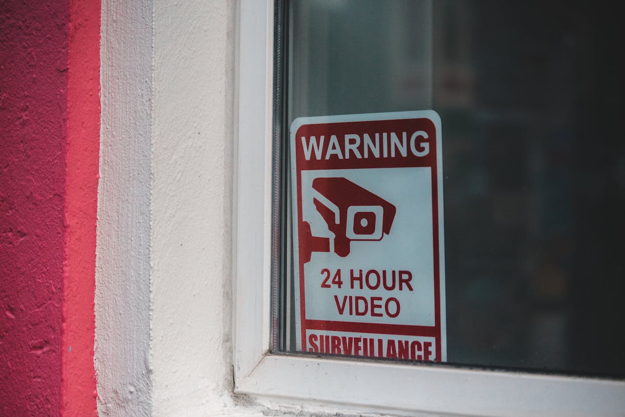 creative-01 Red warning sign of video surveillance placed behind window of building in daytime